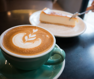 eine Tasse Kaffe im Hintergrund ein Stück Kuchen