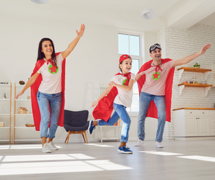 2 Erwachsene und 1 Kind mit Superhelden-Umhang